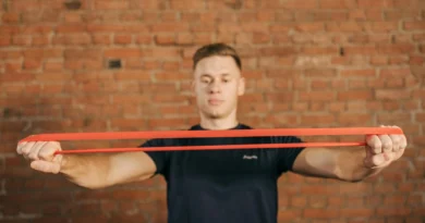 Man stretching a resistance band in front of a brick wall.