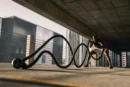 man exercising with large ropes.