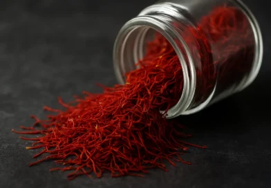 a glass jar on its side spilling out strand of crimson red saffron threads.